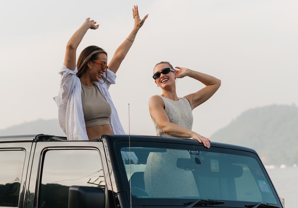 Zwei Frauen genießen in einem Cabriolet das Sonnenlicht